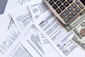 Stack of tax documents and a calculator, referencing TSP withdrawal calculations.